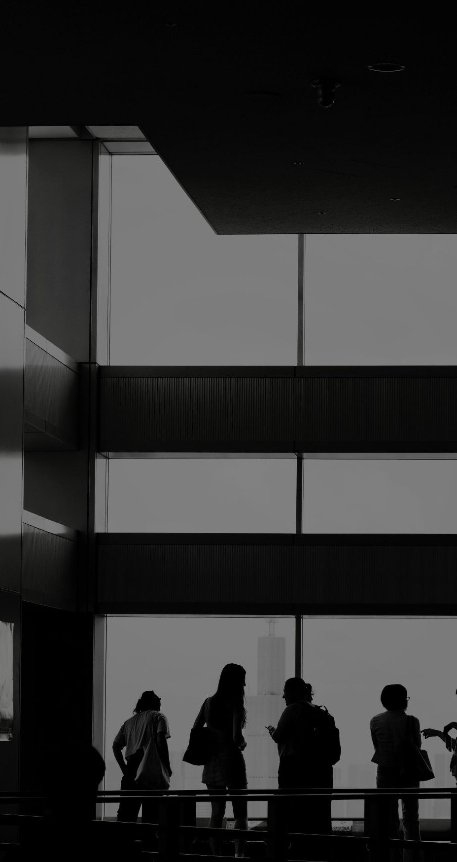 Elevated walkway above a city at dusk with people in silhouette