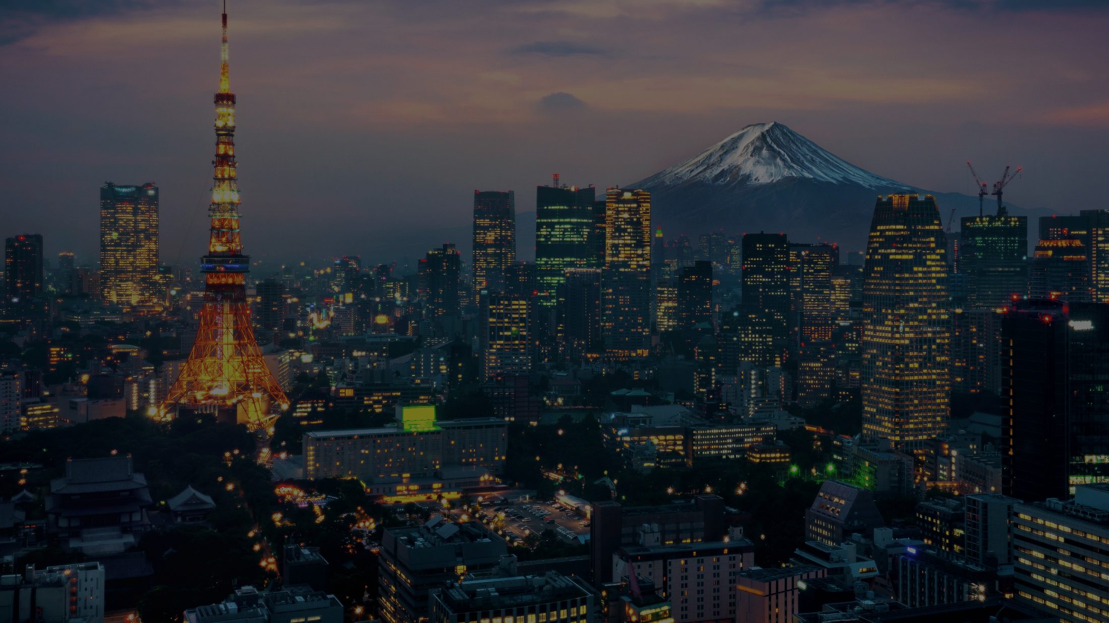 City skyline at dusk with distant mountain, seen from above